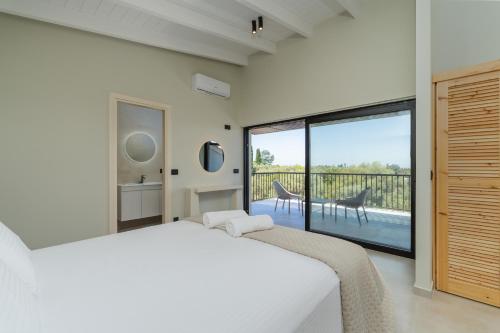 a bedroom with a white bed and a large window at Avelia Villa Tsoukalades in Tsoukalades