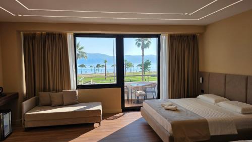 a bedroom with a bed and a couch and a large window at Haris Hotel & Suites in Vlorë