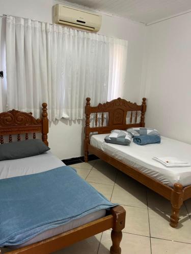 two twin beds in a room with a window at HOTEL ITAPUÃ vg in Várzea Grande