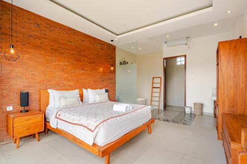 a bedroom with a bed and a brick wall at Villa Sandhyā Tabanan in Tabanan
