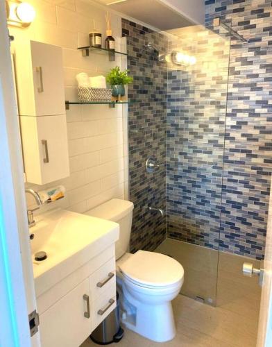 a bathroom with a toilet and a glass shower at KASA Emmas Ocean View in San Juan
