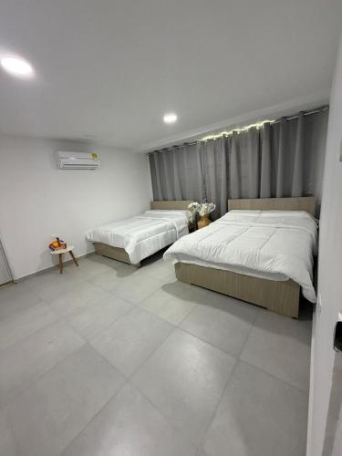 a bedroom with two beds and a tiled floor at Hotel Boutique Trinitarias in Valledupar