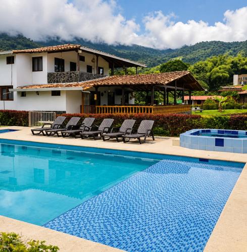 a swimming pool with chairs and a house at Hotel Campestre Alameda in Támesis