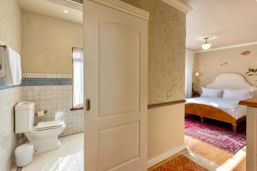 a bathroom with a toilet and a bed in a room at Royva Bo-Kaap in Cape Town