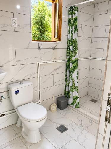a white bathroom with a toilet and a shower at TreeHouse Experience in Vusanje