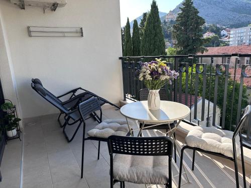 un balcone con tavolo, sedie e un vaso di fiori di Apartman Mango & Mia a Trebinje