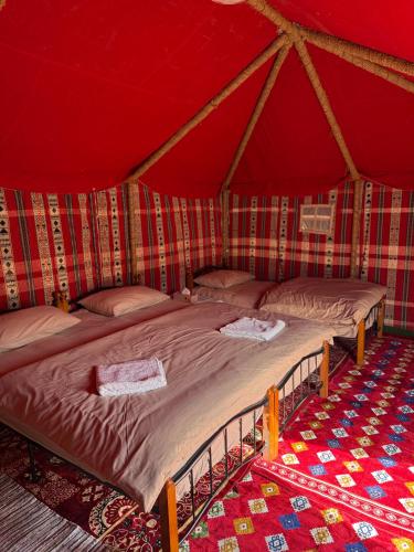 ein Schlafzimmer mit zwei Betten in einem roten Zelt in der Unterkunft Authentic Desert Camp - Al Wasil in Al Wāşil