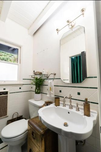 a bathroom with a sink and a toilet and a mirror at Malibu Surf Cottage on Lechuza Beach in Malibu