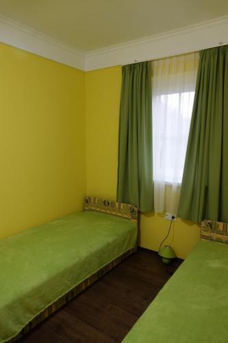 a bedroom with two beds and a window with green curtains at Mesteri Apartman 1A-B in Mesteri