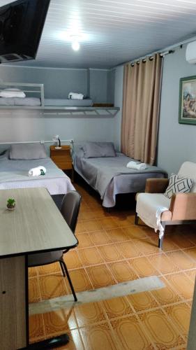 a room with two beds and a table and chairs at Recanto da Matriz - Águas da Prata in Águas da Prata