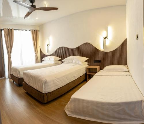 a hotel room with two beds and a ceiling fan at Lagoon Dhigurah in Dhigurah