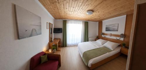 a bedroom with a bed and a couch and a chair at Landhotel Waldmühle in Sankt Georgen im Attergau
