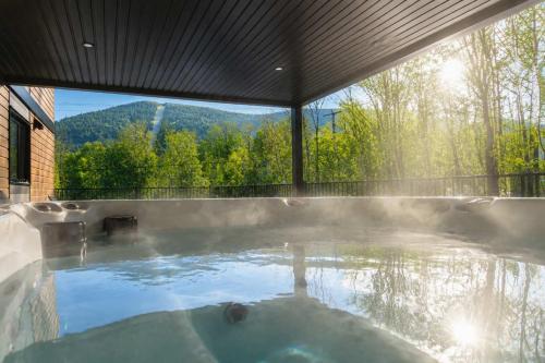 a hot tub with a view of the mountains at Spa Mountains & Ultimate Comfort - Le Jameson in Saint-Philémon