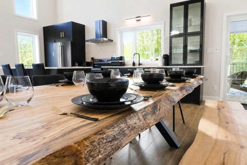 a kitchen with a large wooden table with bowls on it at Spa Mountains & Ultimate Comfort - Le Jameson in Saint-Philémon