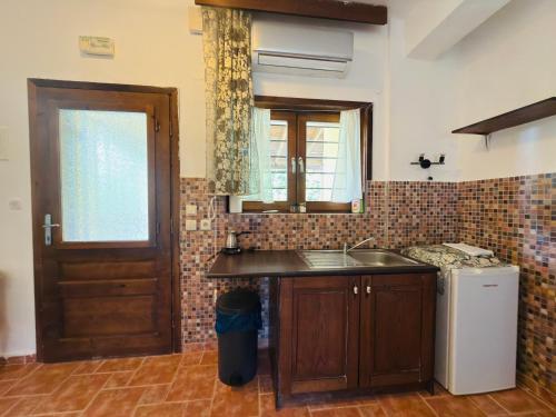 a kitchen with a sink and a refrigerator and a door at Hause Sogambros 2 in Taxiarchis