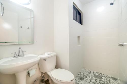 a white bathroom with a toilet and a sink at Valentina Suites by Las Flores Vacation Rentals in Playa del Carmen