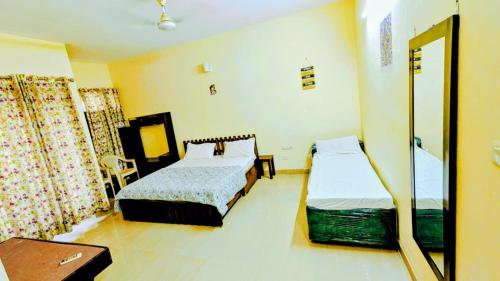 a bedroom with two beds and a table and a mirror at KRISHNA 1 BHK Palace Omaxe in Vrindāvan