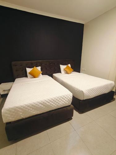 two beds with yellow pillows in a room at Mansarda parkview Hotel in Nyagatare