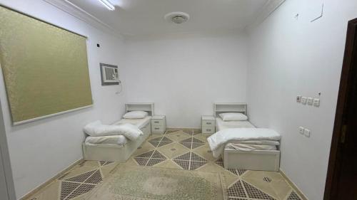 a room with three beds and a greenboard on the wall at اجنحة رحال لشقق الفروشة in Medina