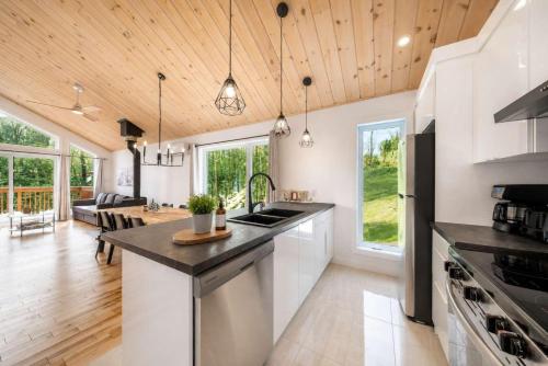 a kitchen with white cabinets and a wooden ceiling at Spa & Foosball - Le WKD in Saint-Philémon