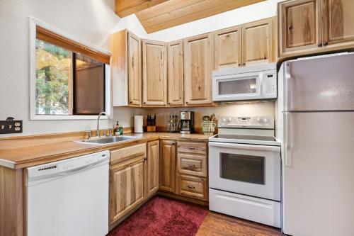 a kitchen with white appliances and wooden cabinets at Grizzly Den in Whitefish