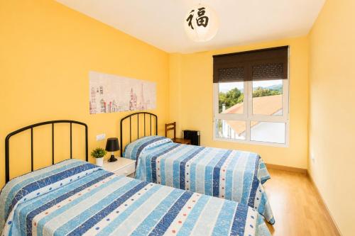 two beds in a bedroom with yellow walls and a window at Apartamento Mar de Carnota in San Mamede de Carnota