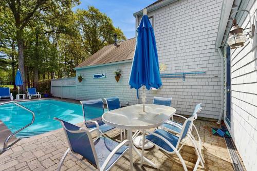 a table and chairs with an umbrella next to a pool at New Seabury Escape in Mashpee
