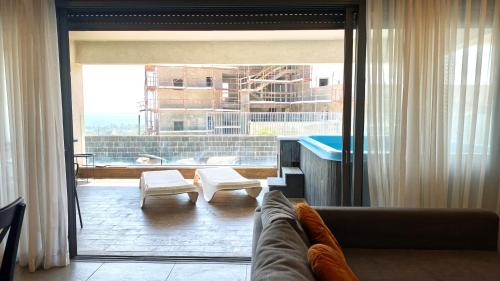 a living room with a couch and a large window at סי כנרת- דירות עם בריכה פרטית מבית בלו מגדל in Migdal
