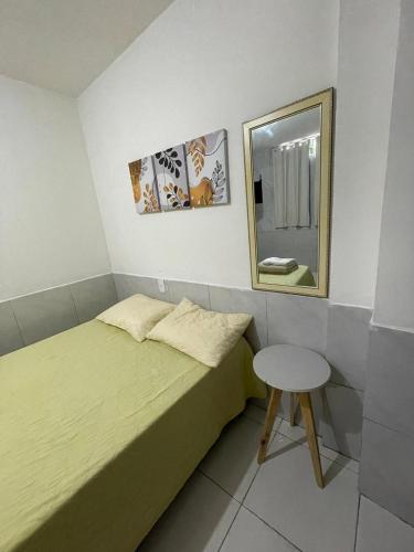 a bedroom with a bed and a mirror and a stool at JARDIM TROPICAL - QUARTO 03 ar-condicionado in Bayeux