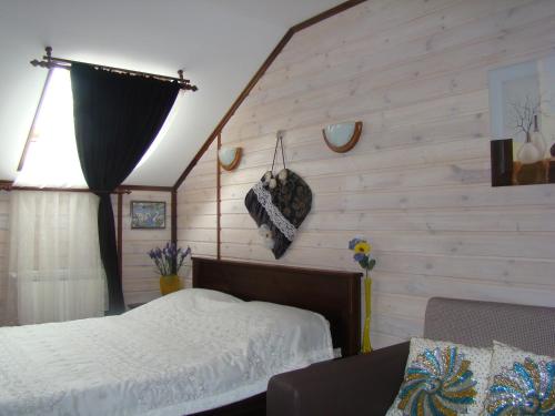 1 dormitorio con 1 cama y pared de madera en Shale Prigranichnoe, en Damachava