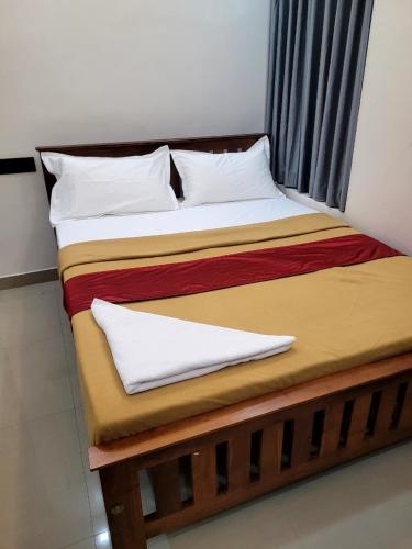a bed in a room with two pillows on it at Hotel Grand Illam in Ernakulam