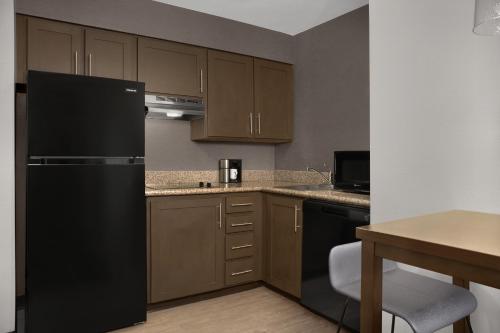 a kitchen with a black refrigerator and wooden cabinets at Residence Inn by Marriott Provo North University in Provo