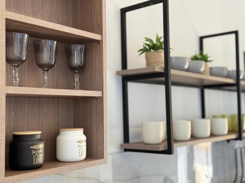 a room with wooden shelves with glasses and a mirror at Sunrise Village Aptera Private Pool Villa in Beritianá