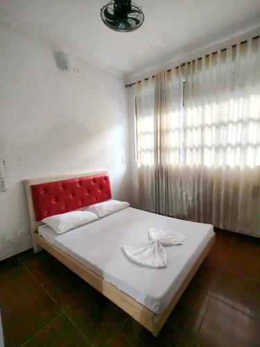 a bedroom with a bed with a red headboard and a window at Villa Tania in Melgar