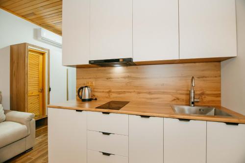 a kitchen with white cabinets and a sink at Villa Mirakula Kvariati in Kvariati