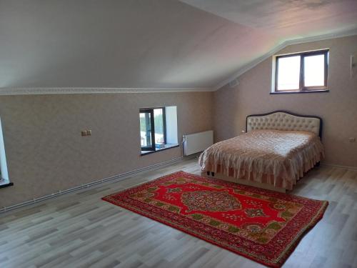 a bedroom with a bed and a rug and two windows at Village in Oğuz