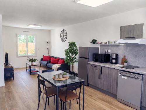 a kitchen and a living room with a table and chairs at Le temps de la pause 1 in Cepoy