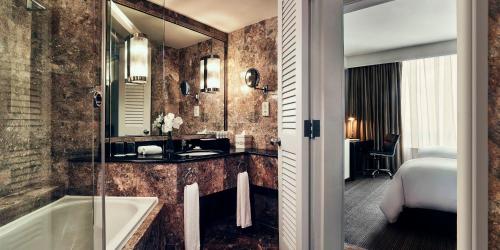 a bathroom with a tub and a sink and a mirror at Pan Pacific Hanoi in Hanoi