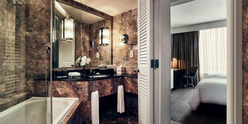 La salle de bains est pourvue d'une baignoire, d'un lavabo et d'un miroir. dans l'établissement Pan Pacific Hanoi, à Hanoï