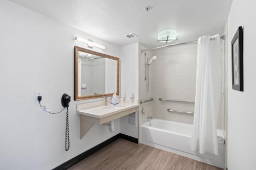 a bathroom with a sink and a tub and a mirror at GreenTree Inn & Suites Phoenix Sky Harbor in Phoenix