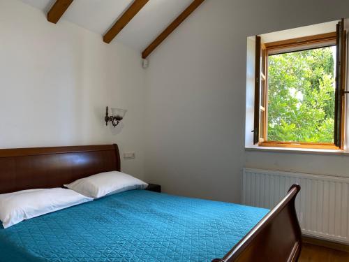 a bedroom with a bed with a blue comforter and a window at Villa Zeleni raj in Omiš