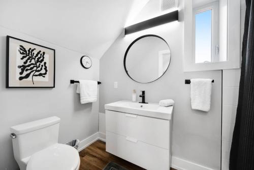 a white bathroom with a toilet and a mirror at Modern 1 Bdrm with Laundry, BBQ, Deck in Welland
