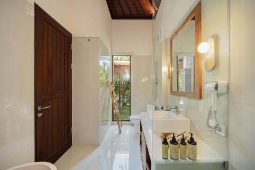 a bathroom with a sink and a toilet and a mirror at Puri Diamond Villas in Tampaksiring