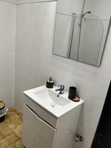 a white bathroom with a sink and a mirror at Conceição Guesthouse in Tavira