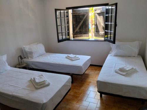 three beds in a room with a window at Conceição Guesthouse in Tavira