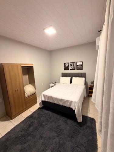 a bedroom with a large bed and a small cabinet at Apart 102 CENTRO in Tubarão