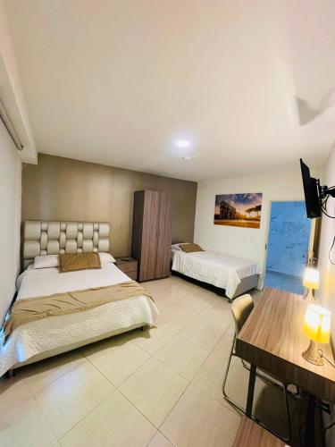 a large bedroom with two beds and a table at Hotel Mall Roma in Pereira