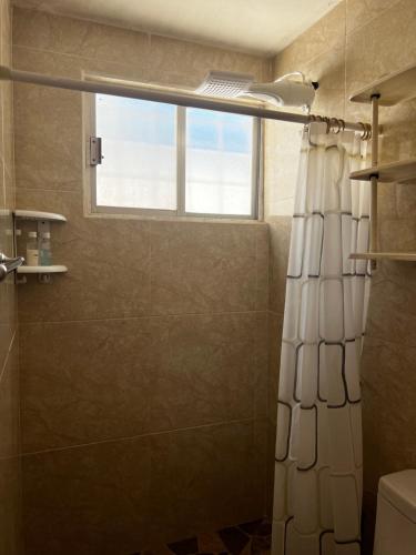 a bathroom with a shower curtain and a window at Casa Múkara del Puerto in Veracruz