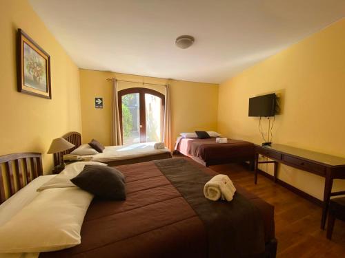 a hotel room with two beds and a desk at Hotel Meliana in Arequipa
