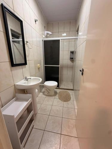 a bathroom with a toilet and a sink and a shower at Apart 102 CENTRO in Tubarão